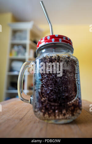 Cola in ein Glas mit einem Griff, rot Deckel mit weißen Flecken&a Edelstahl Trinkhalm. Stockfoto