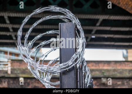 Stacheldraht auf Metall fechten als Abschreckung, Leute aus den Betrieben zu halten. Stockfoto