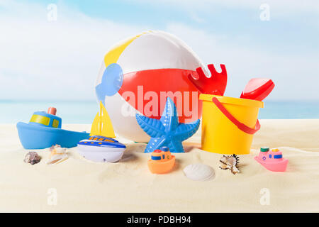 Beach Ball und Eimer mit Spielzeug in Sand und blauer Himmel Stockfoto