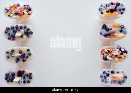 Blick von oben auf die kalte Süße hausgemachte Eis am Stiel mit Früchten und Beeren auf grauem Hintergrund Stockfoto