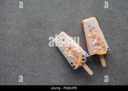 Blick von oben auf die leckere kalte Eis am Stiel auf Sticks auf grauem Hintergrund Stockfoto