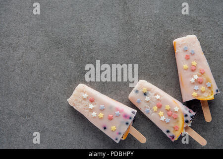 Blick von oben auf die süß lecker Eis am Stiel auf Sticks auf grauem Hintergrund Stockfoto