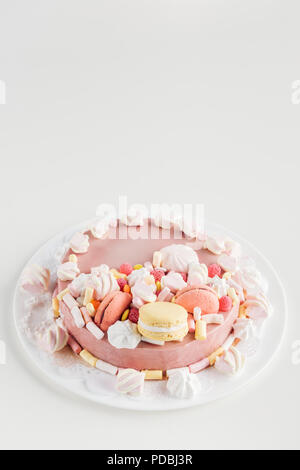 Rosa Kuchen mit Marshmallows und macarons auf weiße Platte mit Kopie Raum Stockfoto