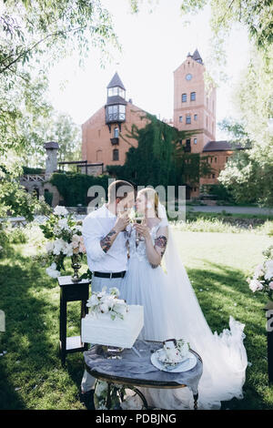 Braut und Bräutigam mit Champagner Gläser im Park küssen Stockfoto