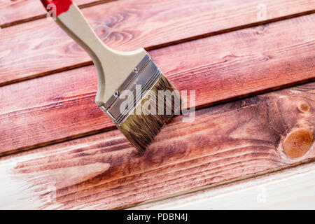 Der Prozess des Malens Holzbretter. Holzbohlen wiederherstellen. Nahaufnahme Foto. Pinsel auf Holz- Textur Hintergrund, Holzschreibtisch. Kopieren Sie Platz Stockfoto