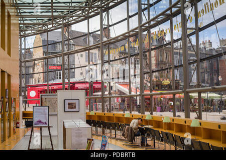 Eine Ansicht aus dem Inneren der moderne Glasfront öffentliche Bibliothek in Honfleur, Normandie, Frankreich mit der antiken Gebäude in der Straße außerhalb Stockfoto