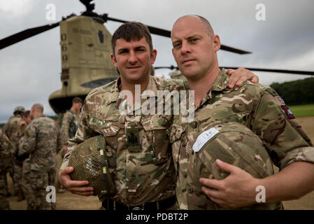 Warrant Officer I Biggs und Sgt. Ross Hastie aus dem 16 Air Assault Brigade HQ, Vereinigtes Königreich, posieren vor einem US Army CH-47 Chinook Hubschrauber nach anhaltendem Airborne Training während der Leapfest an der Universität von Rhode Island, West Kingston, R.I., Aug 4, 2018. Leapfest ist der größte und am längsten bestehende, internationale statische Linie Fallschirm Training und Wettbewerb veranstaltet vom 56. Truppe den Befehl, Rhode-Island Army National Guard hohen Niveau zu fördern technische und Korpsgeist innerhalb der internationalen Gemeinschaft in der Luft. (U.S. Armee Foto von 1 Leutnant Stephen Malone) Stockfoto