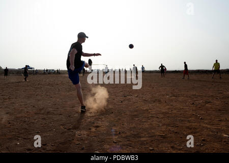 Us-Mitglieder zu Combined Joint Task Force - Horn von Afrika zugeordnet, an einer Partie Fußball mit Kindern aus dem nahe gelegenen Dorf, außerhalb von Chebelley Dorf, Dschibuti, Aug 3, 2018. Über 30 Soldaten und Piloten die sich freiwillig für die Öffentlichkeitsarbeit Veranstaltung von der 404Th zivilen Angelegenheiten Bataillon organisiert. (U.S. Air National Guard Foto von Master Sgt. Sarah Mattison) Stockfoto