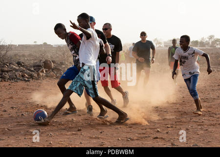 Us-Mitglieder zu Combined Joint Task Force - Horn von Afrika, beteiligen sich in einer Partie Fußball mit Kindern aus dem nahe gelegenen Dorf, außerhalb von Chebelley Dorf, Dschibuti, Aug 3, 2018. Über 30 Soldaten und Piloten die sich freiwillig für die Öffentlichkeitsarbeit Veranstaltung von der 404Th zivilen Angelegenheiten Bataillon organisiert. (U.S. Air National Guard Foto von Master Sgt. Sarah Mattison) Stockfoto