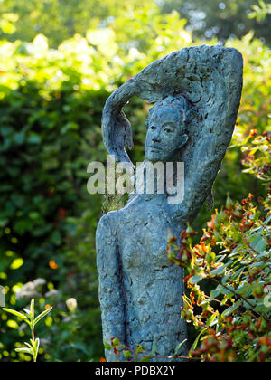 Skulptur einer Frau im Chenies Manor Garden. Detail eines sonnendurchfluteten Spider mit Gewinde aus ihrer Hand. Stockfoto