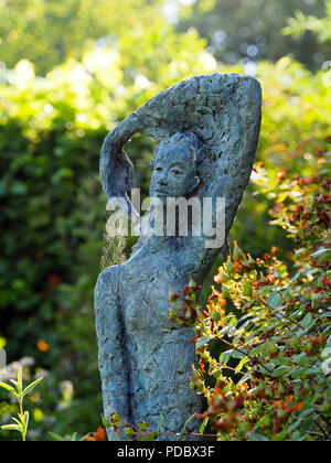 Skulptur einer Frau im Chenies Manor Garden. Detail eines sonnendurchfluteten Spider mit Gewinde aus ihrer Hand. Stockfoto