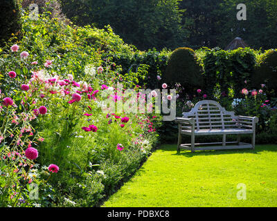 Einen erholsamen Ort im Chenies Manor Garden, Buckinghamshire zu sitzen. Pretty Pink und Weiß in die Blume Grenze mit Lilien, Kosmos, Dahlien und cleome. Stockfoto