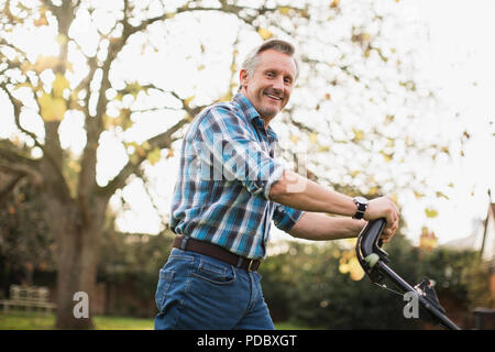 Porträt Lächeln älterer Mann mähen Rasen Stockfoto