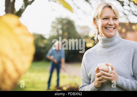Portrait lächelnd, glücklich reife Frau trinkt Kaffee im Herbst Yard Stockfoto