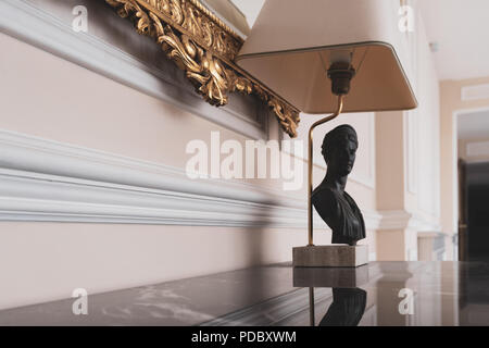 Dekorative Lampe mit antiken Büste auf einem Granit Tisch unter einem goldenen Rand eines Bildes in einem Innenraum Stockfoto