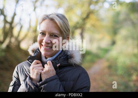 Porträt Lächeln, zuversichtlich, reife Frau in Parka in Wäldern Stockfoto