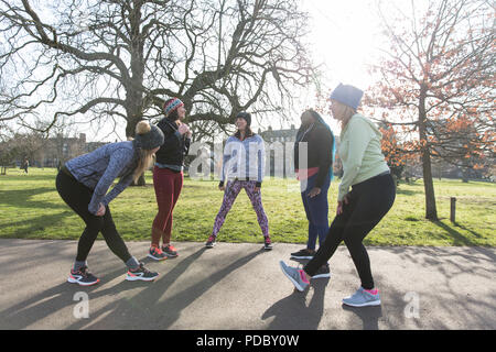 Läuferinnen Stretching und Sprechen im sonnigen Park Stockfoto