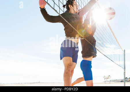 Männer spielen Beachvolleyball am sonnigen Strand Stockfoto