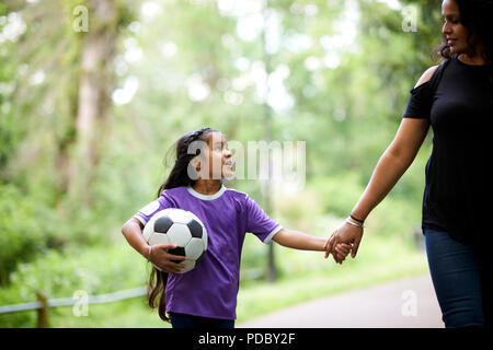 Liebevolle Mutter und Tochter mit Fußball, Hände halten Stockfoto