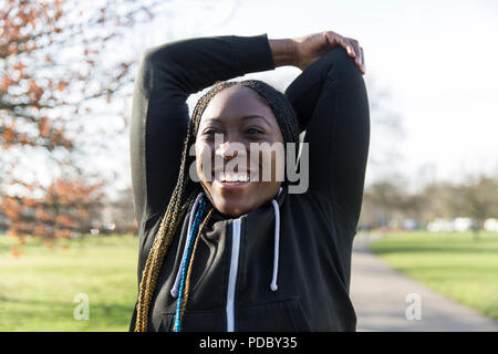 Portrait zuversichtlich Läuferin stretching Arms in Park Stockfoto