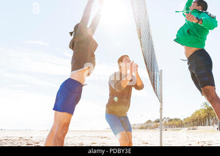 Männer spielen Beachvolleyball am sonnigen Strand Stockfoto