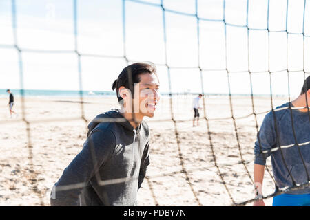 Lächelnd Mann spielt Beachvolleyball am sonnigen Strand Stockfoto