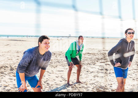 Männer spielen Beachvolleyball am sonnigen Strand Stockfoto