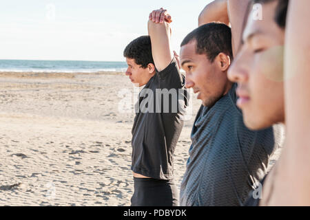 Männliche Läufer stretching Arme auf Sunny Beach Stockfoto