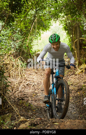 Glückliche Menschen Mountainbiken auf Trail im Wald Stockfoto