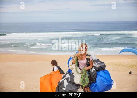 Porträt Lächeln, selbstbewussten weiblichen Gleitschirm mit Ausrüstung an sonnigen Strand Stockfoto
