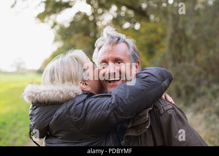 Portrait fröhlicher, verspielter Reifes Paar umarmen in Park Stockfoto