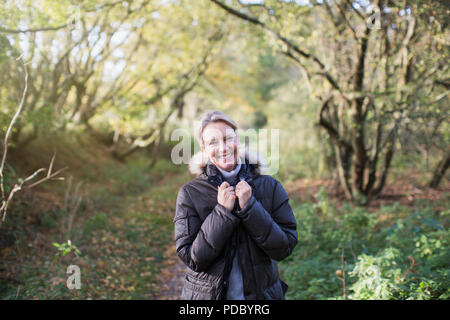 Portrait zuversichtlich, reife Frau in Parka im sonnigen Herbst Wald Stockfoto