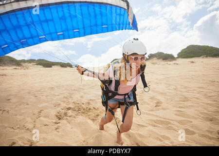 Lächelnd weibliche Gleitschirm mit Fallschirm am Strand Stockfoto