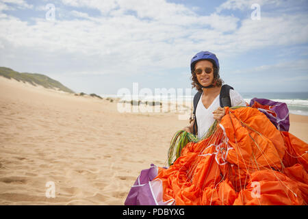 Porträt Lächeln männlichen Gleitschirm mit Fallschirm am Strand Stockfoto