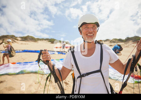 Reife männliche Gleitschirm auf Strand mit Ausrüstung Stockfoto