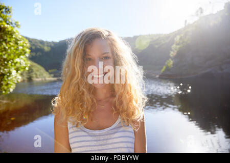 Porträt Lächeln, selbstbewussten jungen Frau an sonnigen Sommer See Stockfoto