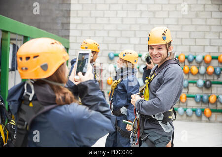 Frau mit smart phone fotografieren Mann Vorbereitung Zip Line Geräte Stockfoto