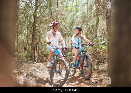 Vater und Tochter Mountainbiken auf Trail im Wald Stockfoto