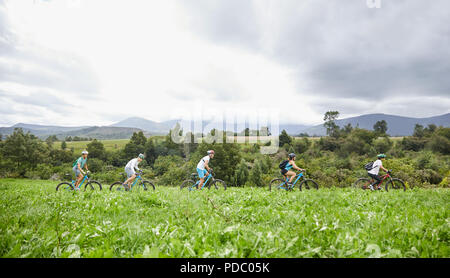 Freunde Mountainbiken im idyllischen, abgelegenen Feld Stockfoto