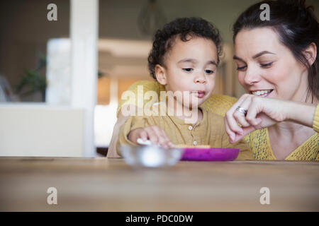 Mutter feeding baby Sohn am Tisch Stockfoto