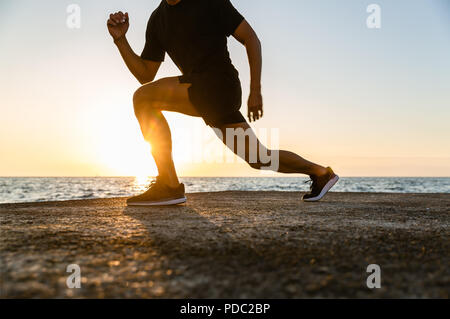 7/8 Schuß des athletischen Mann stürzt während der Ausbildung am Meer Stockfoto