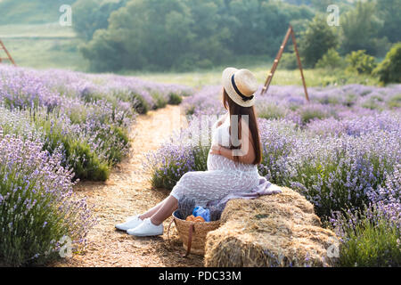 Seitenansicht der schwangeren Frau sitzt auf der Heu Ballen in violett Lavendel Feld Stockfoto