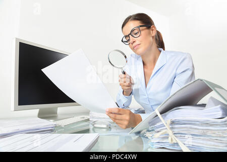 Business Woman in Office Dokumente und Verträge mit Lupe am Schreibtisch auf weißem Hintergrund sitzen Stockfoto