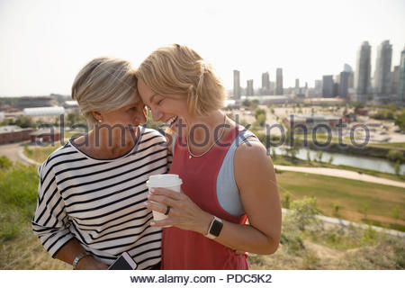 Liebevolle Mutter und Tochter mit Kaffee im sonnigen städtischen Park