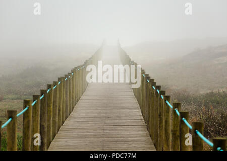 Dune Holzsteg in Richtung Strand, in einer nebligen späten Sommernachmittag. Im Norden von Portugal. Stockfoto