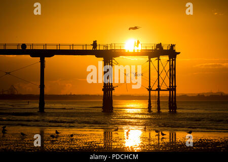 Menschen beobachten Sonnenuntergang von Salburn Victirian's Pier. Saltburn am Meer, North Yorkshire, England. Vereinigtes Königreich. August 2018. Stockfoto