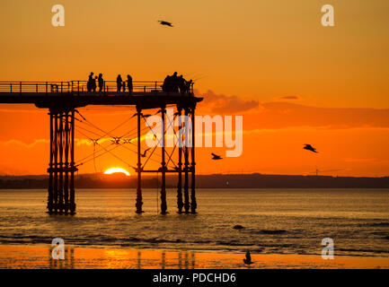 Menschen beobachten Sonnenuntergang von Salburn Victirian's Pier. Saltburn am Meer, North Yorkshire, England. Vereinigtes Königreich. August 2018. Stockfoto