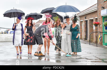 Brighton, UK. 9 Aug, 2018. Ein Mitglied der Kurs Personal fegt ein Pfad für diese Damen in der nassen Wetter Brighton Rennen Marathonbet Sommerfest der Racing Ladies Day Event: Simon Dack/Alamy leben Nachrichten Stockfoto