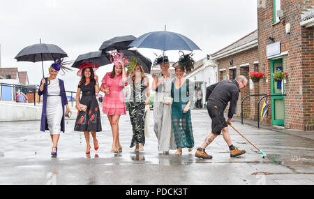 Brighton, UK. 9 Aug, 2018. Ein Mitglied der Kurs Personal fegt ein Pfad für diese Damen in der nassen Wetter Brighton Rennen Marathonbet Sommerfest der Racing Ladies Day Event: Simon Dack/Alamy leben Nachrichten Stockfoto