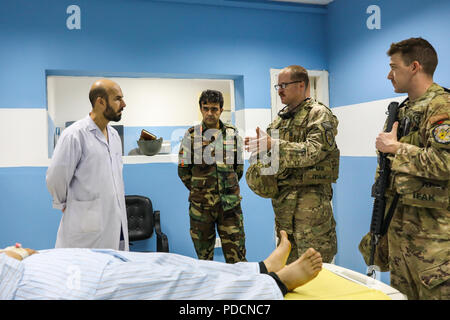 Der PROVINZ KANDAHAR, Afghanistan (5. August 2018) - U.S. Navy Leutnant Cdr. Justin S. Clark, Radiologie Techniker für Kandahar Airfield Rolle der NATO III Multinationale medizinische Einheit, spricht mit afghanischen in der Radiologie, 5. August 2018, während einer medizinischen Beratung Besuch bei Kandahar regionale militärische Krankenhaus, Camp Held in Kandahar, Afghanistan. Mitarbeiter aus der Rolle III Durchführung Routinemäßige Besuche auf KRMH zu trainieren und Beratung afghanischen medizinischen Personal. (U.S. Armee Foto: Staff Sgt. Neysa Canfield/TAAC-Public Affairs) Stockfoto